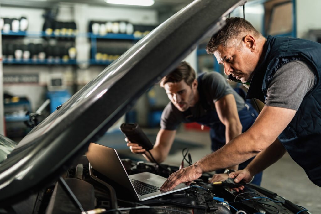 auto repairmen using computer while working car diagnostic in se